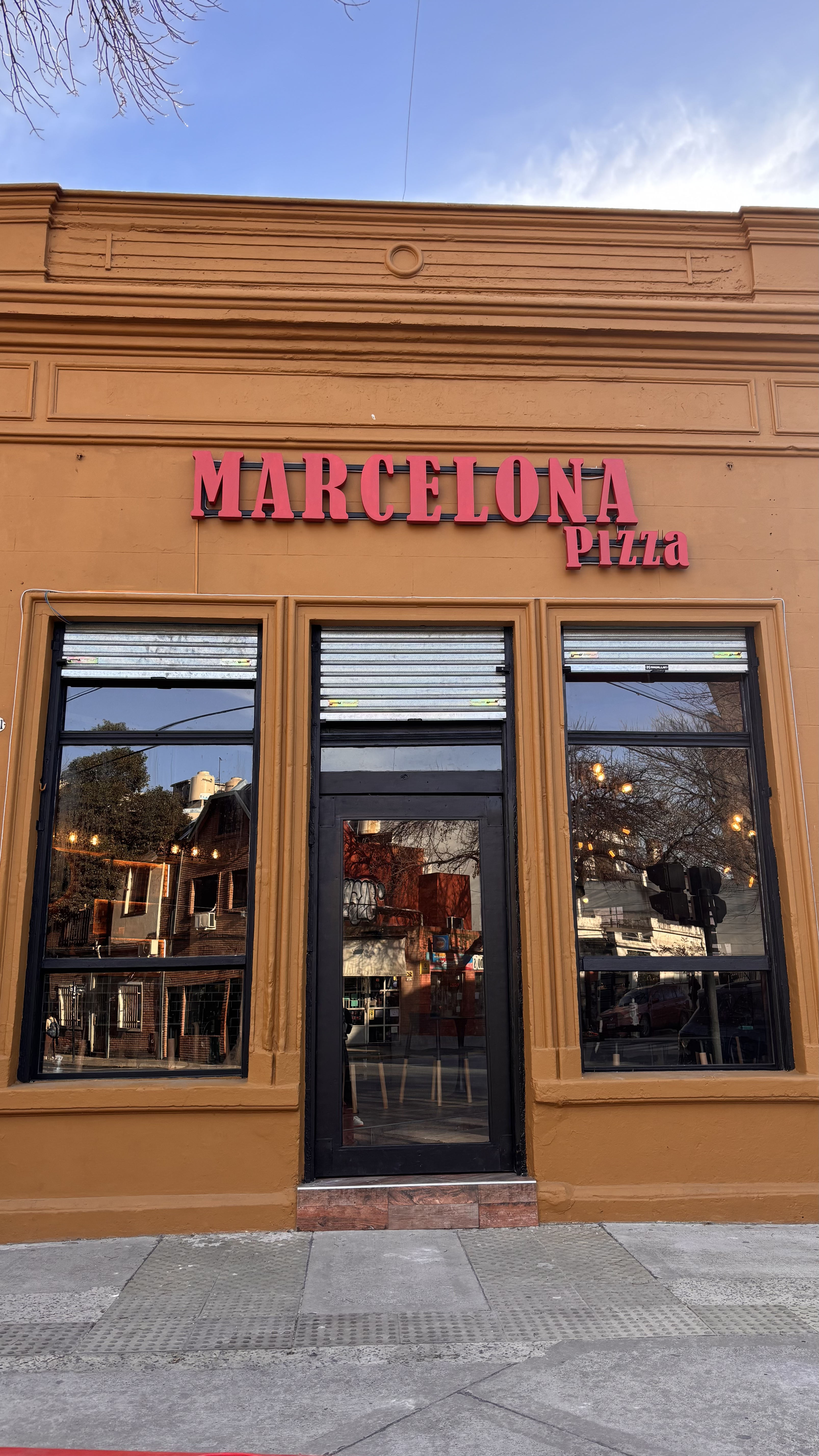 Fachada de Marcelona Pizza con letras rojas y puertas negras